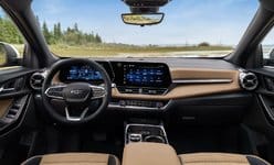 Modern car interior featuring a digital dashboard, steering wheel, and leather seats with a scenic view ahead.
