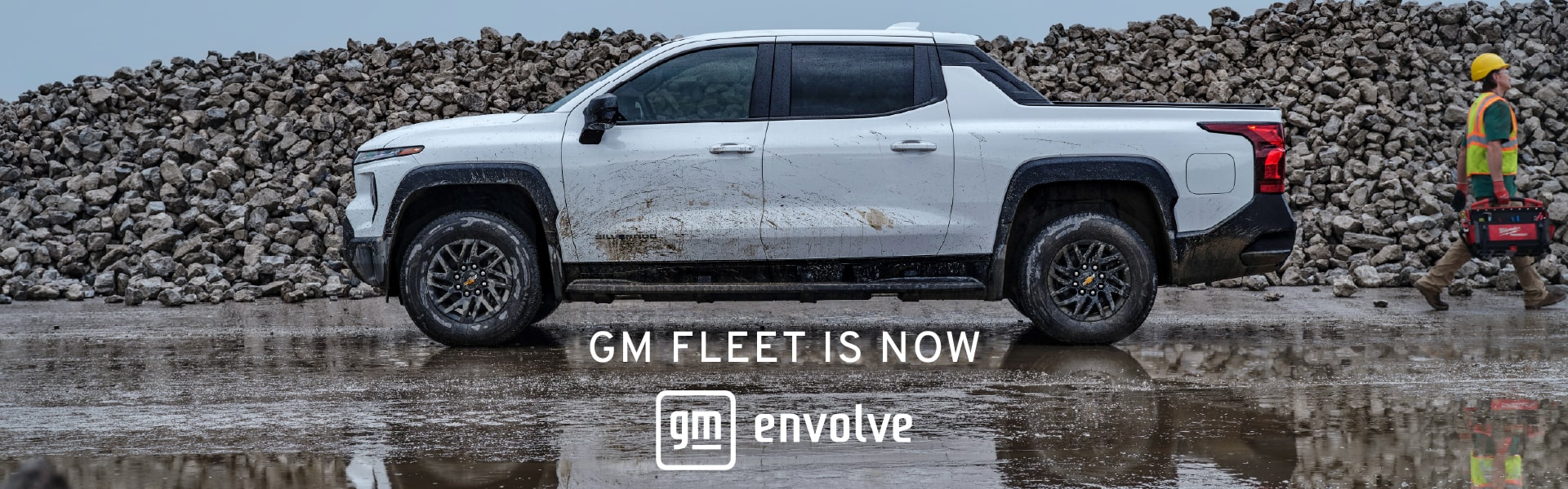 White GM truck on muddy surface, construction worker nearby; text reads "GM Fleet is now Evolve".