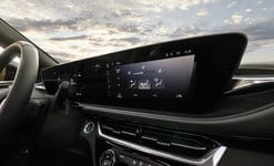Modern car dashboard with digital display showing climate controls under a cloudy sky.