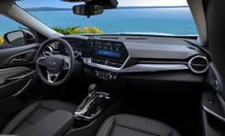 Modern car interior with sleek dashboard, touchscreen display, and ocean view through the windshield.