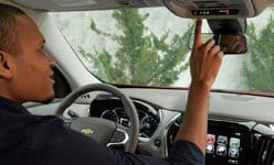 Man inside a Chevrolet car using the overhead console controls while parked.