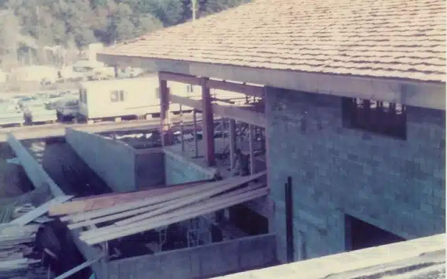 Construction site of a large brick building, surrounded by scaffolding and wooden planks.